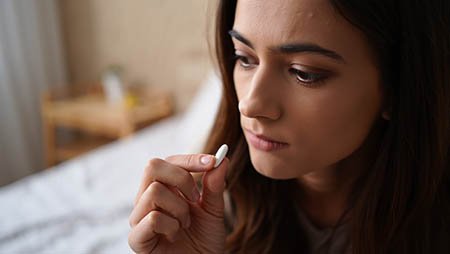 Девушка пьет белую таблетку